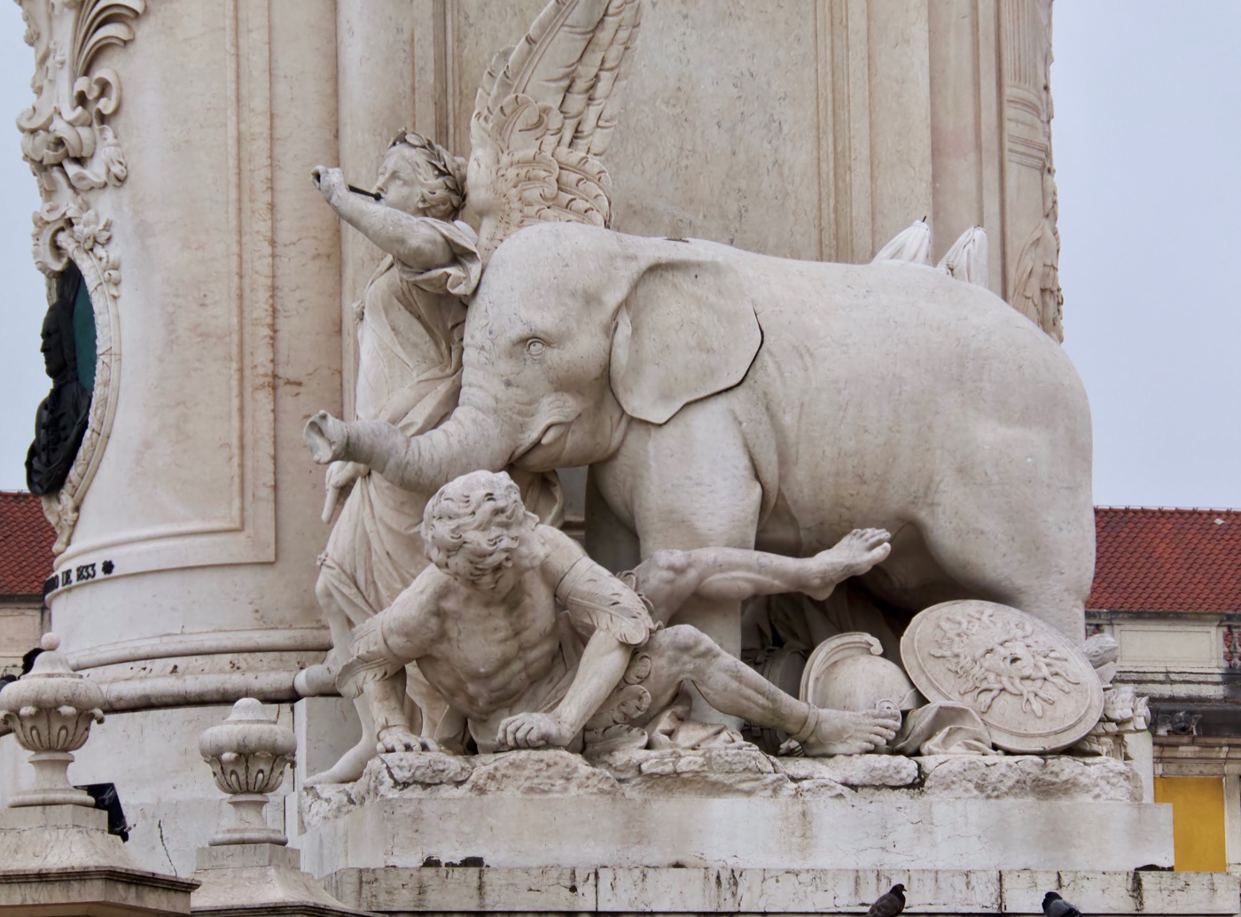 Stone elephant with its trunk outstretched among the allegorical figures at the base of the José I monument